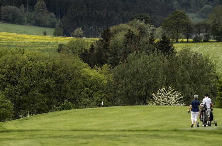 Pärchen geht mit Golfbags über den Golfplatz im Sauerland