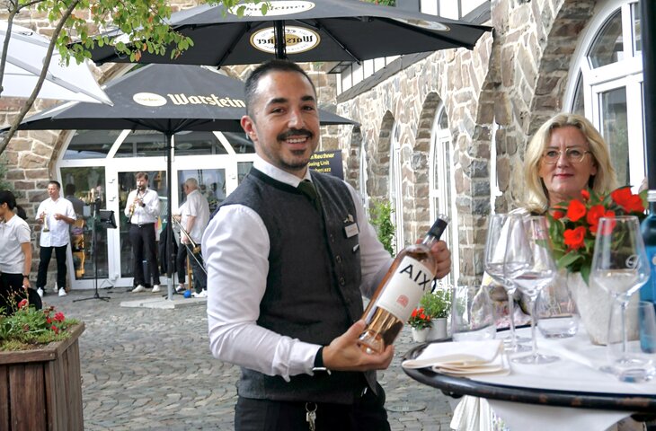Kellner serviert eine Flasche Wein beim Sommerfest im Hotel Deimann