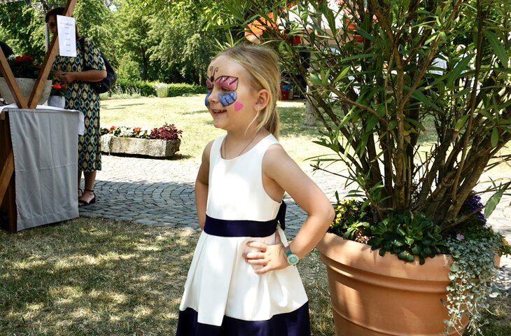 Mädchen präsentiert ihre Kinderschminke beim Sommerfest im Hotel Deimann