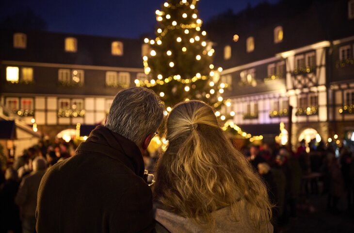 Mann und Frau stehen eng zusammen und schauen auf den Weihnachtsmarkt im Hotel Deimann