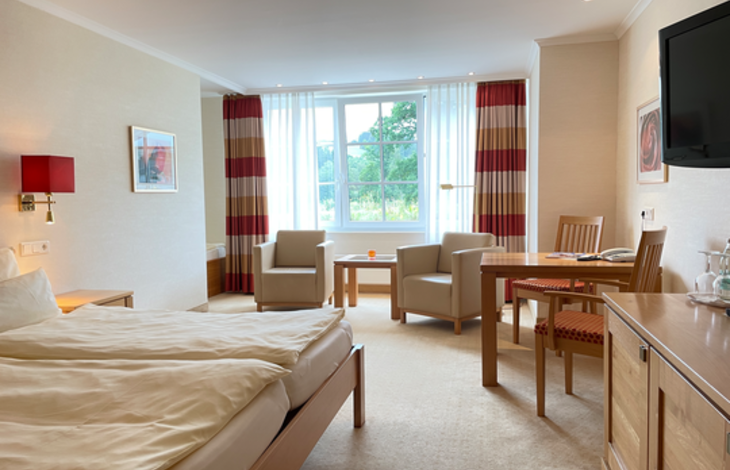 Das Doppelzimmer Gutshof Knollenblick im Romantik- und Wellnesshotel Deimann mit zahlreichen Sitzecken und großen Fenstern 