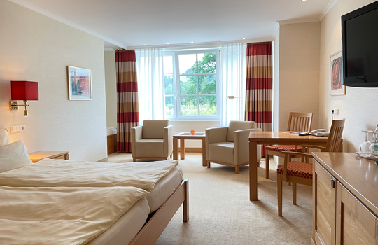 Das Doppelzimmer Gutshof Knollenblick im Romantik- und Wellnesshotel Deimann mit zahlreichen Sitzecken und großen Fenstern 