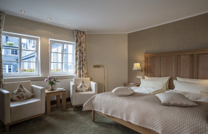 Eine Aufnahme eines großen Hotelzimmers mit Blick auf das frisch gemacht Bett und den Wohnbereich