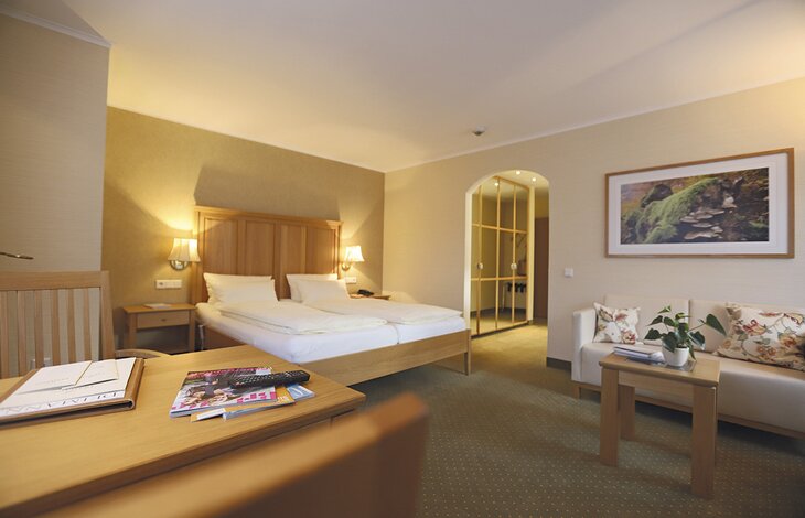 Ein Gesamtüberblick über das großzügige Doppelzimmer Gutshof Innenhof des Romantik- und Wellnesshotels Deimann mit zwei gemütlichen Sitzecken 