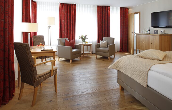Die gemütliche Sitzecke mit großen Fenstern des Doppelzimmers Holzkontor aus dem Romantik- und Wellnesshotel Deimann