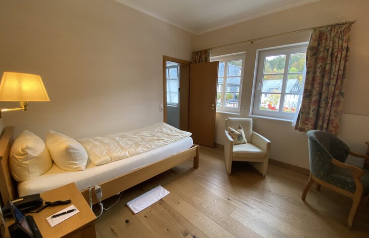 Ein gemütliches Hotelzimmer mit Einzelbett und einem Sessel