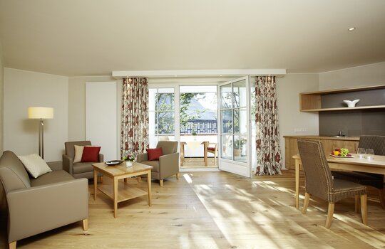 Einsicht in das große Wohnzimmer mit gemütlichen Sitzmöglichkeiten der Junior Suite "Holzkontor"