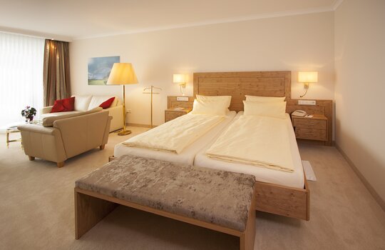 Ein frisch bezogenes Bett im Familienzimmer des Hotels mit einer Couch im Hintergrund