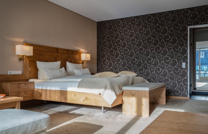 Einblick in das Schlafzimmer mit gemusterter Tapete der Junior Suite "Innenhof"