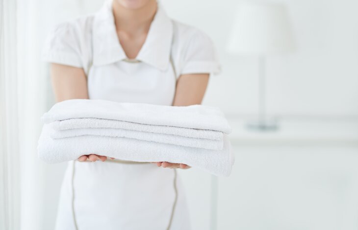 Eine Mitarbeiterin hält einen Stapel weißer Handtücher in ihren Händen