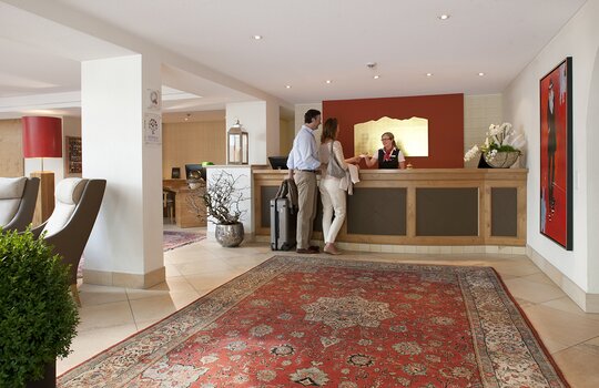 Eine Rezeptionistin überreicht zwei Hotelgästen ihre Zimmerkarte für das Romantik- und Wellnesshotel Deimann 