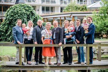 Die gesamte Familie Deimann steht im grünen Hotelgarten auf einer Brücke 