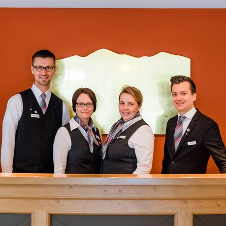 Vier Mitarbeiter der Rezeption des Romantik- und Wellnesshotels Deimann lächeln in die Kamera 