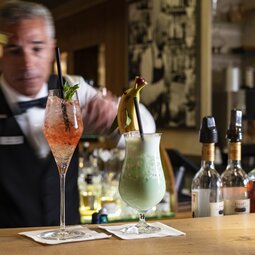 Ein Barkeeper bereitet zwei bunte, fruchtige Cocktails vor 