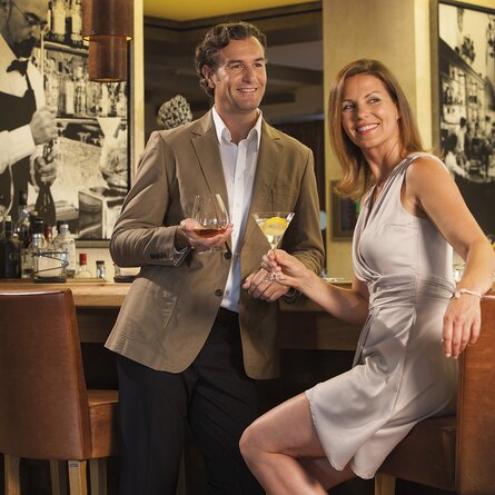 Ein Pärchen genießt Abends ihre Cocktails an der Bar 