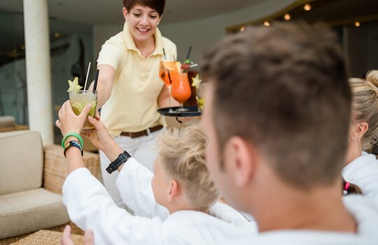 Detailaufnahme einer Kellnerin welche gerade die mitgebrachten Cocktails auf ihrem Tablett an die Gäste verteilt