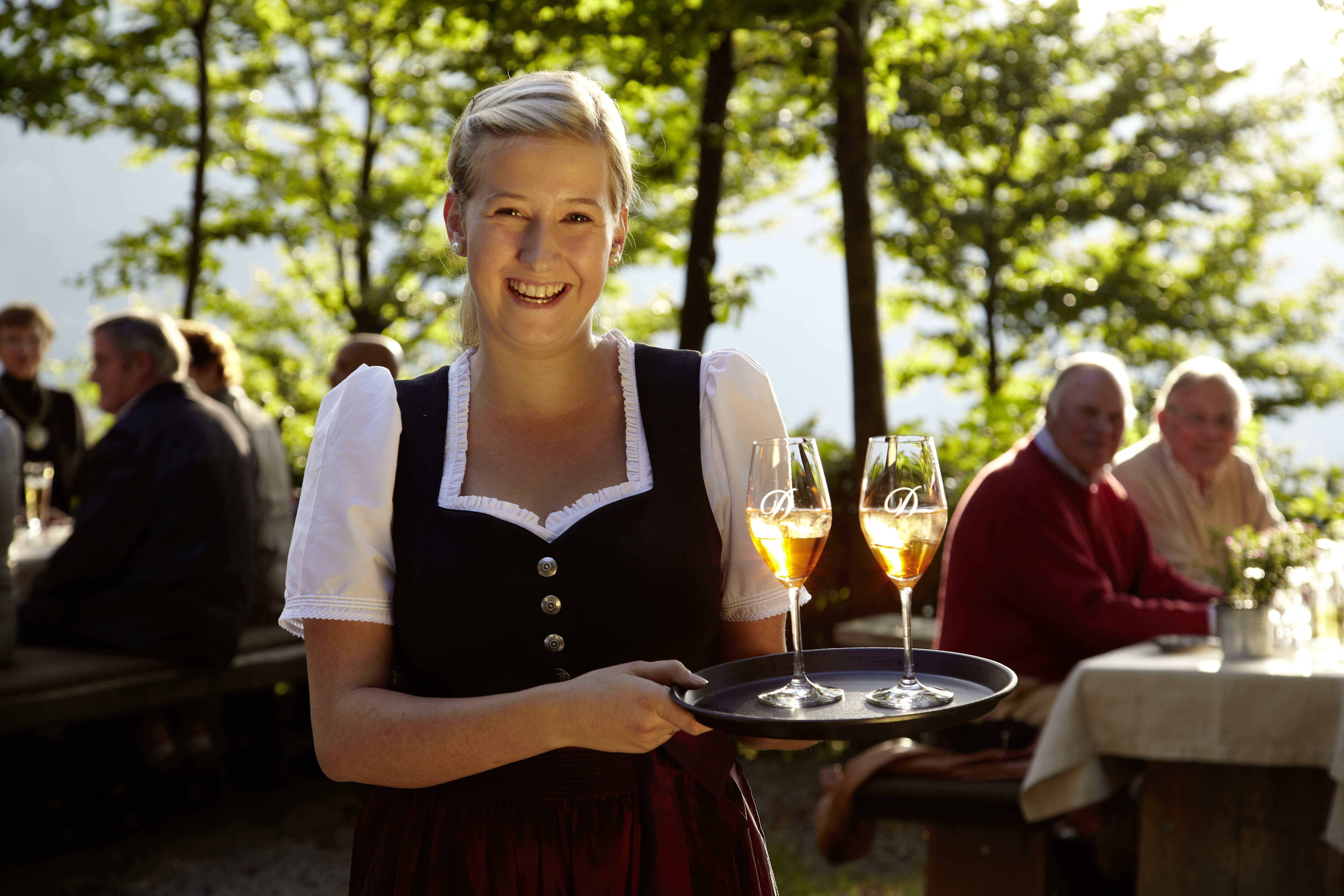 Eine Frau in traditioneller Tracht mit einem Tablet in der Hand im Biergarten der Knollenhütte