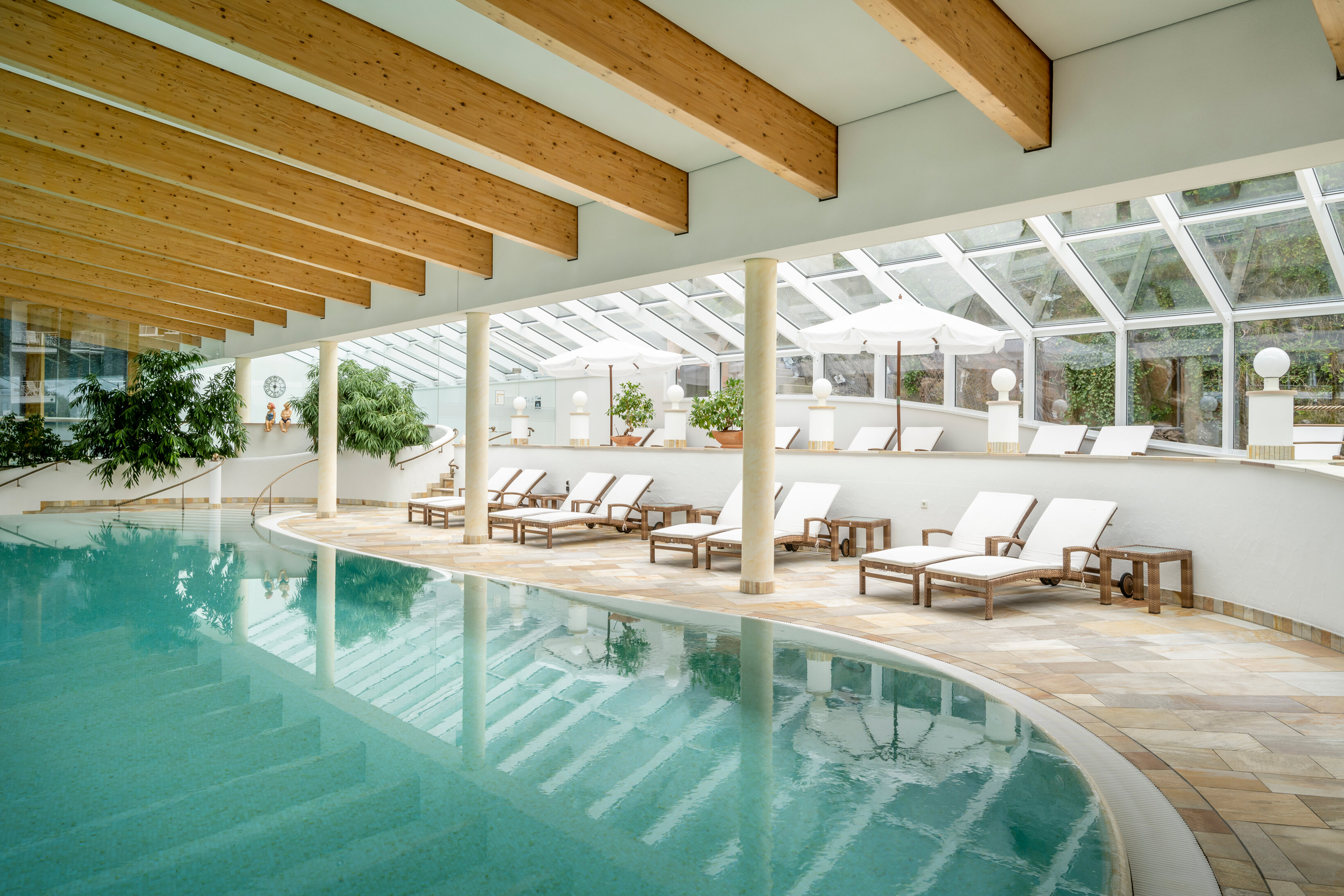 Mehrere Liegen stehen neben dem Innenpool des Hotels