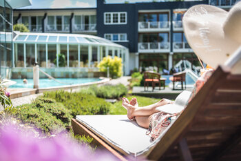 Eine Dame liegt mit ihrem Sonnenhut auf einer Sonnenliege im Wellnesshotel Deimann in NRW 