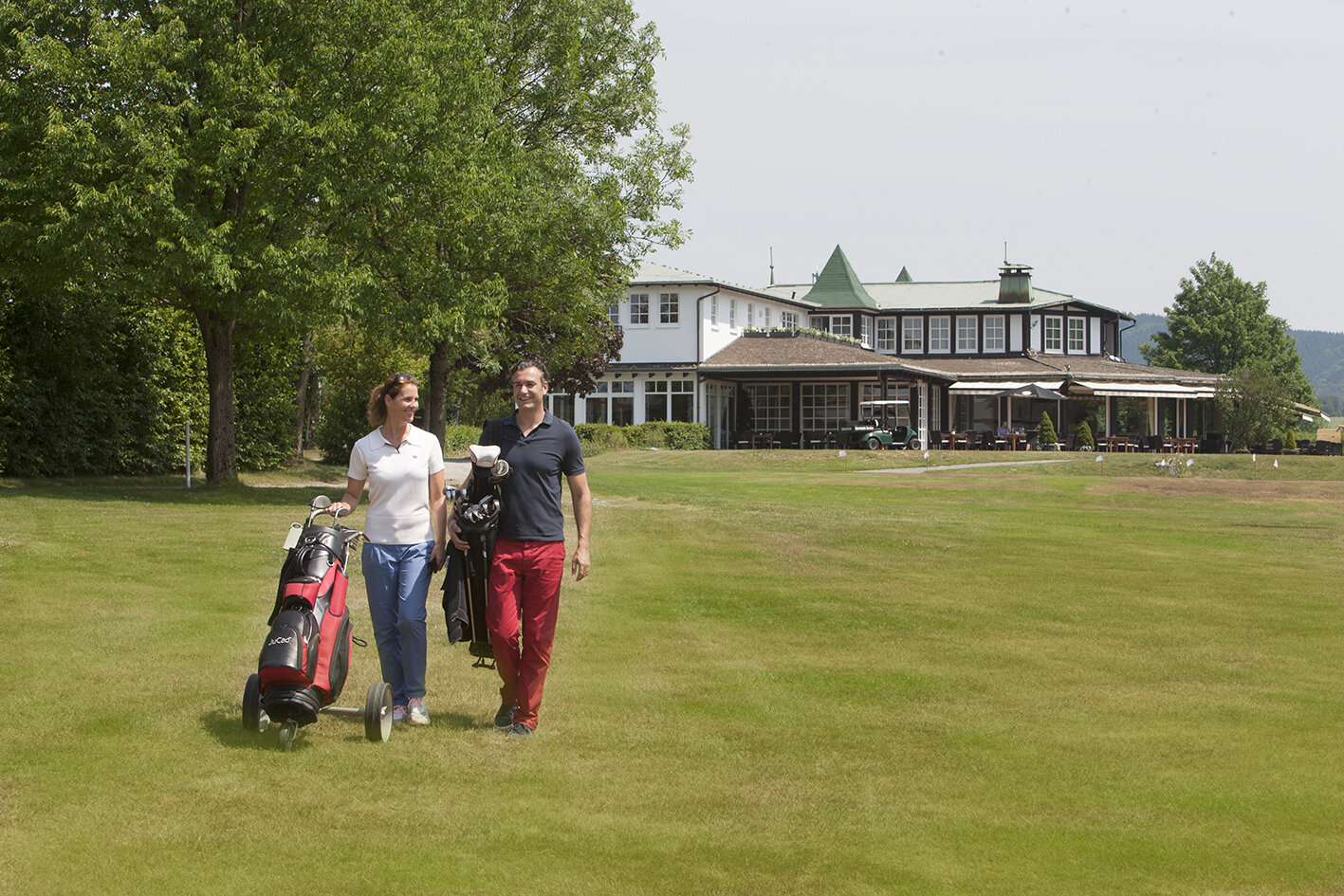 Zwei Gäste des Golfhotels in NRW bringen ihre Caddys auf den Golfplatz 