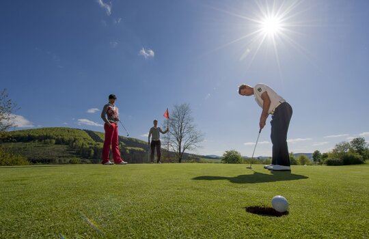 Drei Personen auf einem Golfplatz beim Golf spielen 