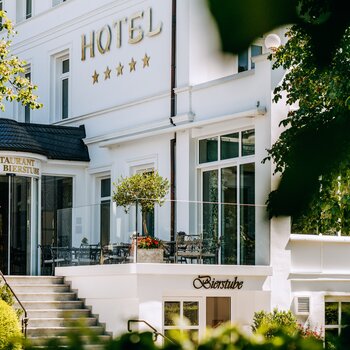 Blick auf den Eingang eines Hotels mit weißer Fassade.