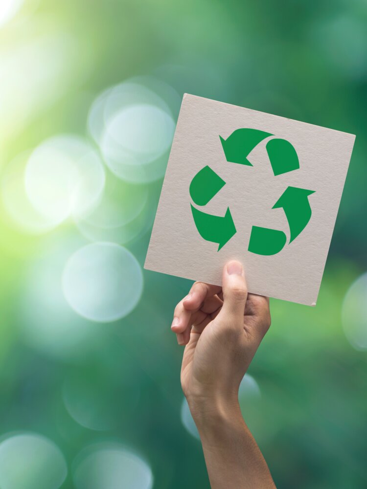 Hand hält ein Schild mit dem Recycling Logo hoch