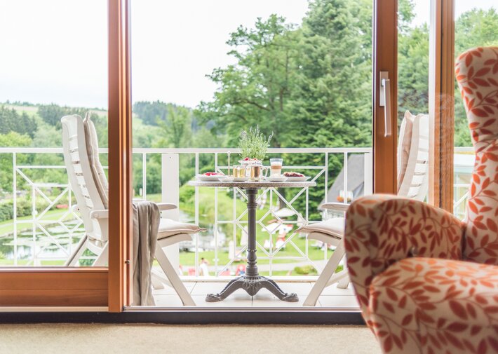 Geöffnete Balkontür in der Juniorsuite im Haupthaus mit Teichblick