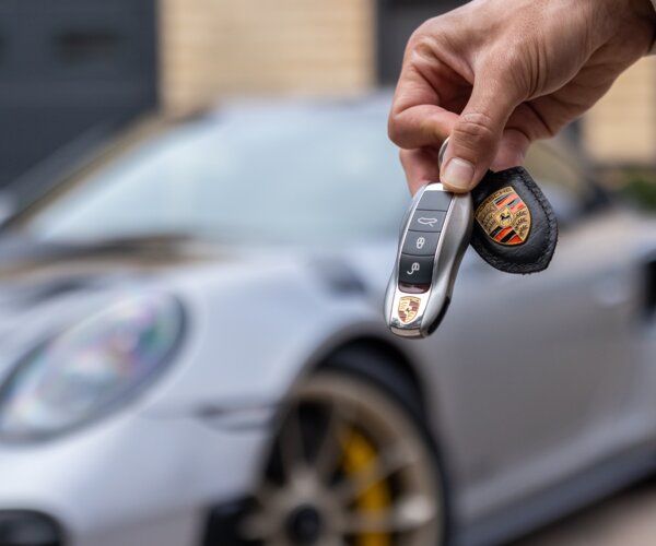 Porsche Schlüssel mit Porsche im Hintergrund