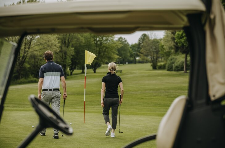 Blick aus dem Golfcaddy auf Pärchen auf dem Golfplatz Hotel Deimann 