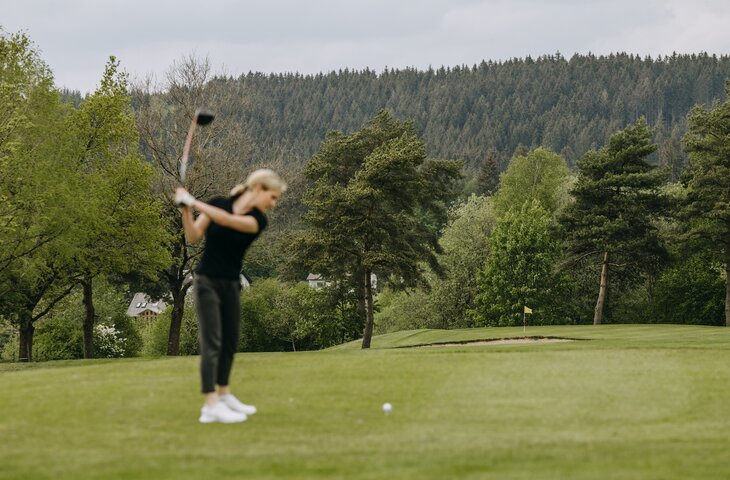 Frau beim Abschlag auf dem Golfplatz im Sauerland