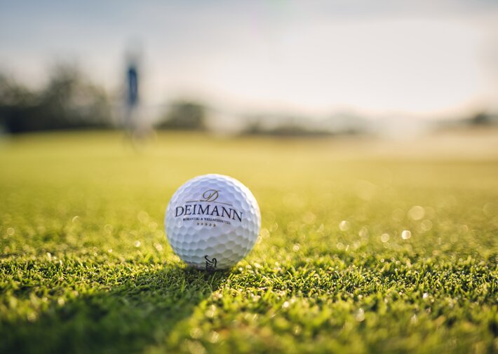 Golball auf grünem Rasen mit Aufdruck Hotel Deimann
