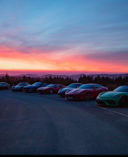 Mehrere Porsche Wagen stehen bei Sonnenuntergang nebeneinander