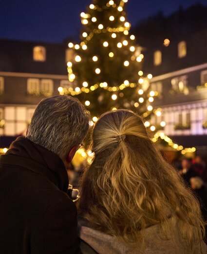 Mann und Frau stehen eng zusammen und schauen auf den Weihnachtsmarkt im Hotel Deimann